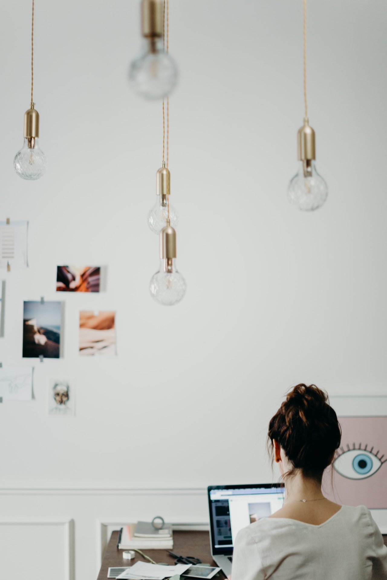 Home-office-Frau-die-ihren-laptop-benutzt-mit-goldenen-Haengelampen Home-office-Frau-die-ihren-laptop-benutzt-mit-goldenen-Haengelampen